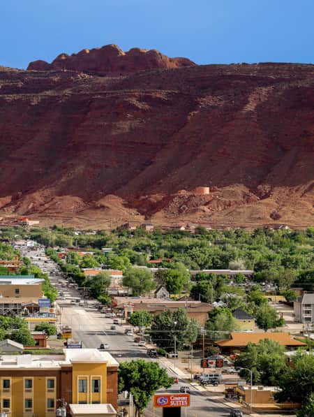 Panoramic shot of a town at the base of red sandstone cliffs.