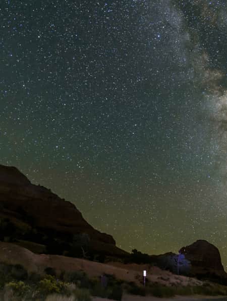 A natural bridge illuminated by the stars in the night sky.