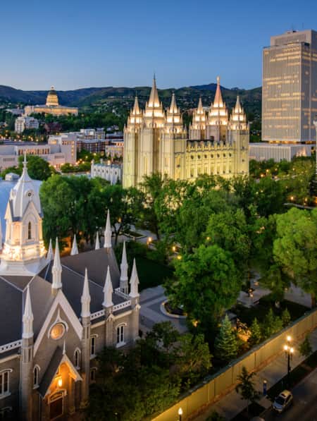 An aerial view of religious buildings with spires illuminated at night.