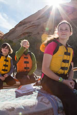 A group of people rafting along a river flowing through a canyon.