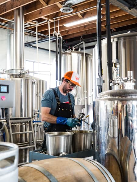 A man stands in a room surrounded by brewing equipment.