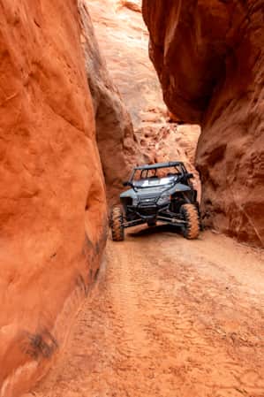 An ATV making a tight turn through a narrow slot canyon.