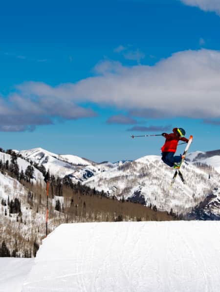 A skier performing a trick in mid-air while coming off a jump.