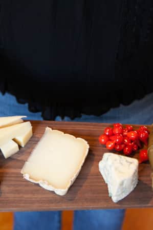 A charcuterie board featuring candied walnuts, various cheeses, and pickled vegetables.
