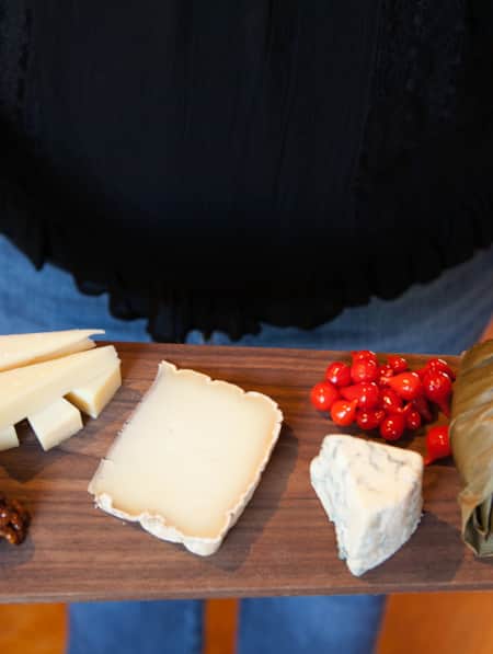 A charcuterie board featuring candied walnuts, various cheeses, and pickled vegetables.