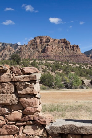 A wall made from many rocks with a cut-out, set in front of a distant mountain range.