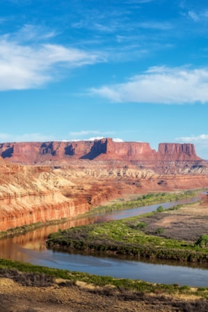 An expansive view of red rock monuments with a river flowing through.