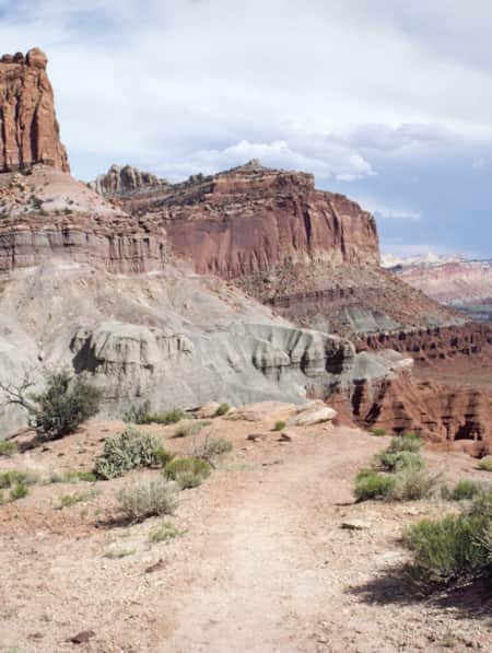 A sandy trail set against large red rock formations in the desert.