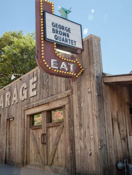 A wooden building with a sign featuring an arrow pointing to the front door that reads "Eat."