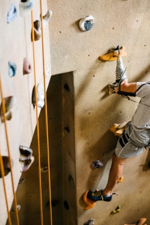 A person rock climbing on an indoor climbing wall.