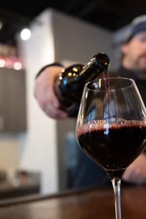 A close-up view of a man pouring wine into a glass.