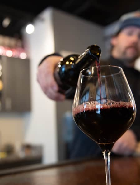 A close-up view of a man pouring wine into a glass.