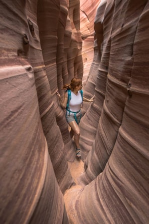 A woman hiking through a narrow slot canyon.