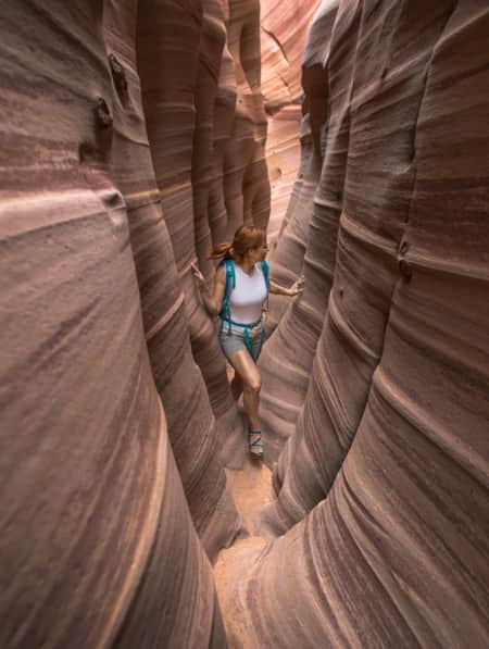 A woman hiking through a narrow slot canyon.