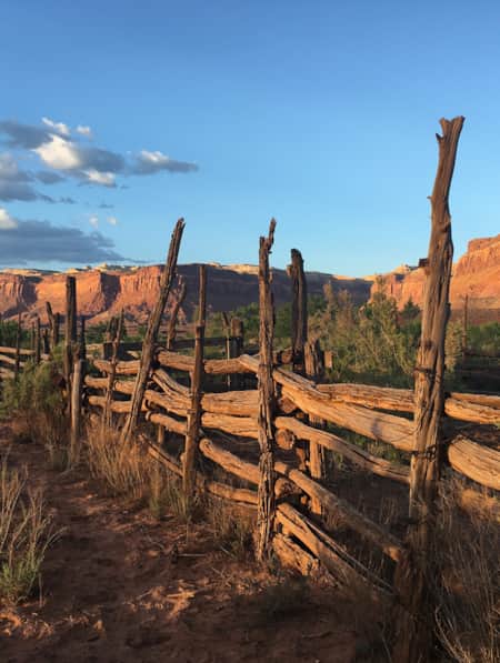 An old fence made of rustic wood in front of an expansive landscape of red rock monuments and plateaus.