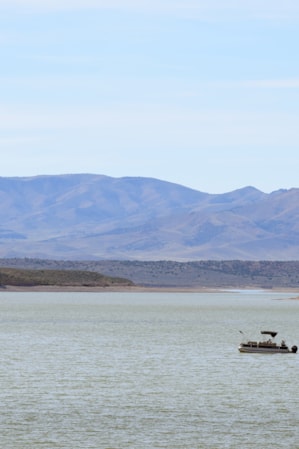 A lake with a boat and mountains in the background.