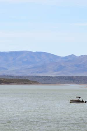 A lake with a boat and mountains in the background.