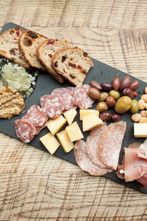 Charcuterie board with meats, cheeses, olives, almonds, and breads artfully arranged on a serving platter.