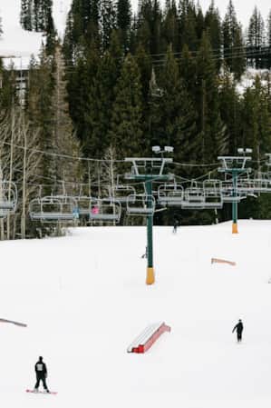 Skiers and snowboarders in the terrain park at Brighton Ski Resort, with a ski lift above them.