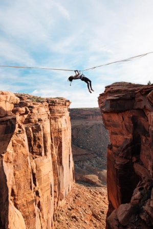 A woman harnessed to a rope, pulling herself across a canyon on a rope secured to each side.