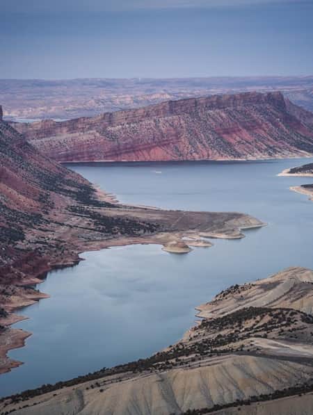 An aerial view of a wide canyon leading into a body of water, which connects to a larger lake.
