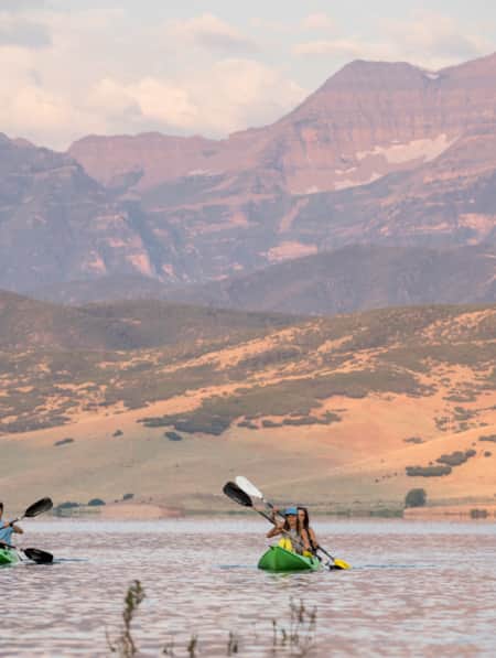 People kayaking on a lake with mountains in the distance.