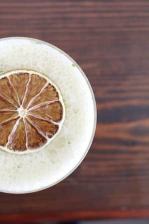 Top view of a drink with foam and a slice of citrus.