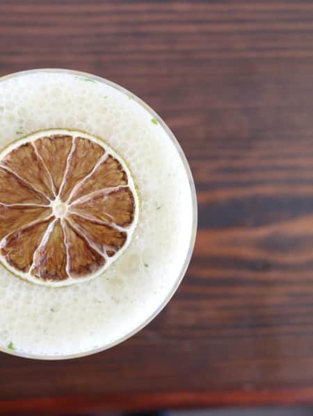 Top view of a drink with foam and a slice of citrus.