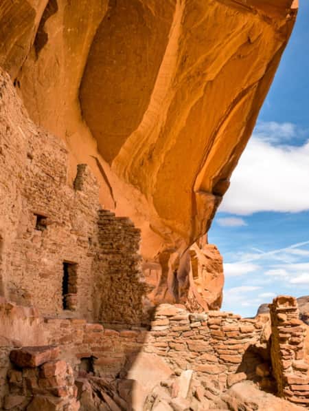 Ruins built into the side of a large red rock feature.