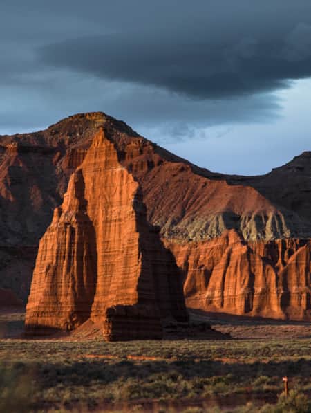 A cliff face of a rocky mountain range, illuminated by the setting sun.