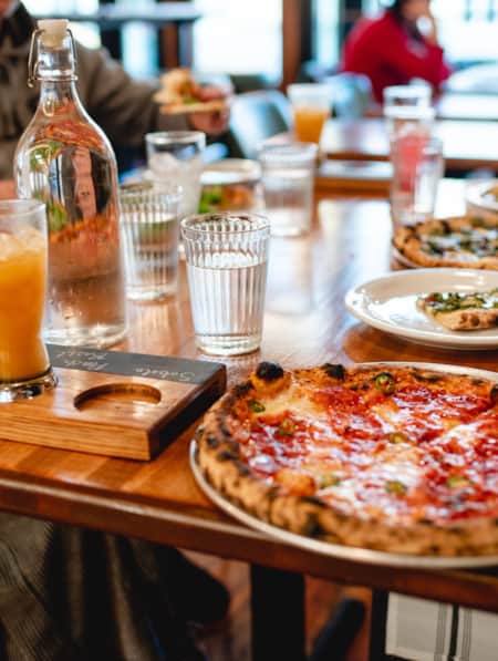 People sitting at a table, sharing and enjoying multiple pizzas.