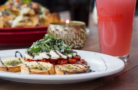 A plate of bruschetta with nachos in the background.