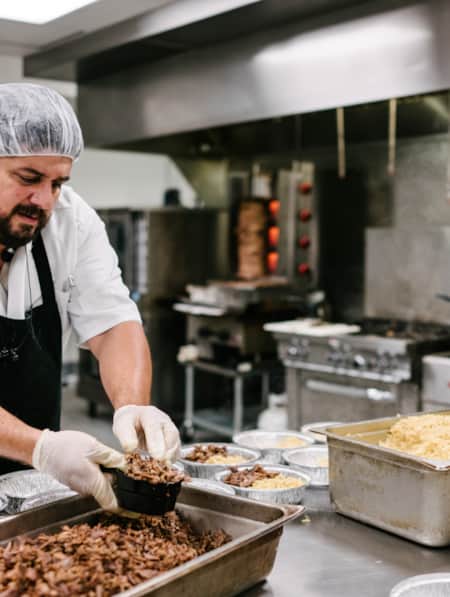 A cook preparing pre-made meals in an industrial kitchen.