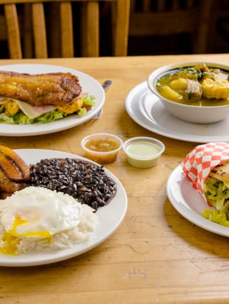 A wooden table with four plates of food arranged on it.
