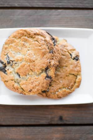 Two chocolate chip cookies placed on a white rectangular plate.