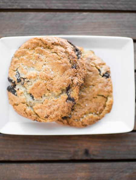 Two chocolate chip cookies placed on a white rectangular plate.