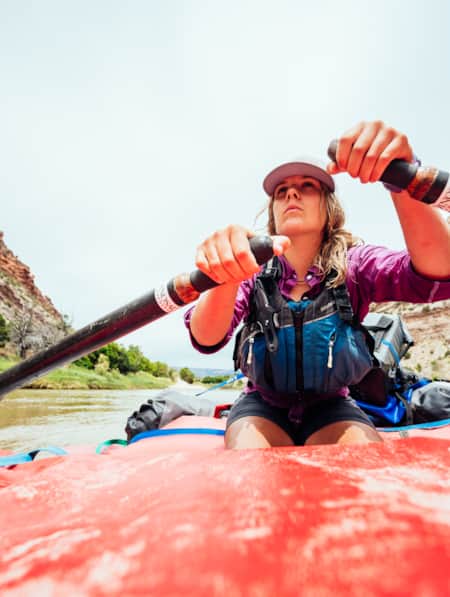 A woman rowing through a river, with tall cliffs rising on each side.