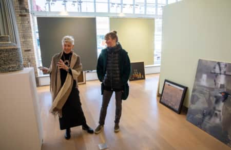 Two women in an art museum, smiling and discussing a piece of artwork.