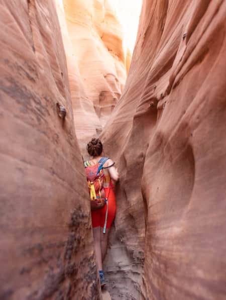 A woman hiking through a narrow slot canyon.