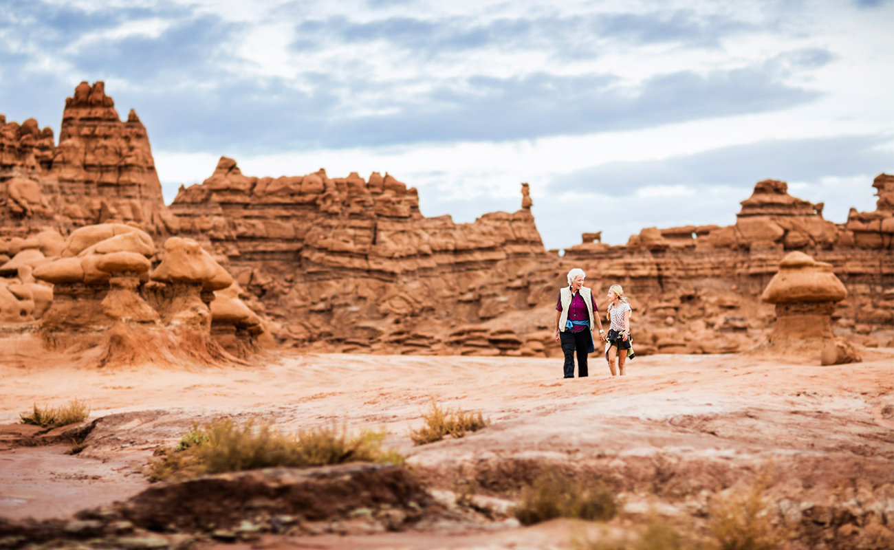 An adult and child hiking through the red rock formations at Goblin Valley State Park.