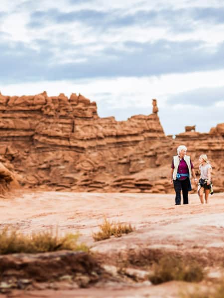 An adult and child hiking through the red rock formations at Goblin Valley State Park.