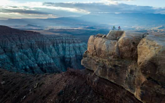 Two riders perched on the edge of the Gooseberry Mesa trail.