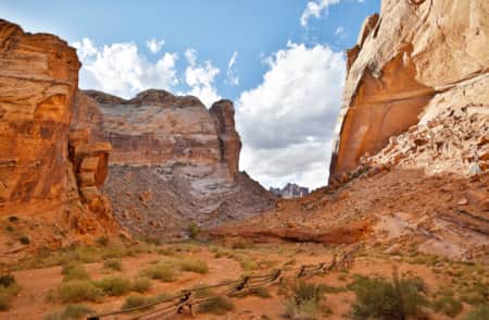 A small canyon of red rock with rocky fields on each side.