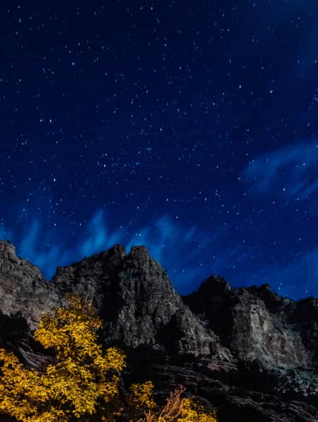 Grey rocky mountain peaks illuminated by the stars of the night sky.