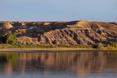 The clay bluffs along the Green River glow before sunset; a great blue heron fishes in the shallows.