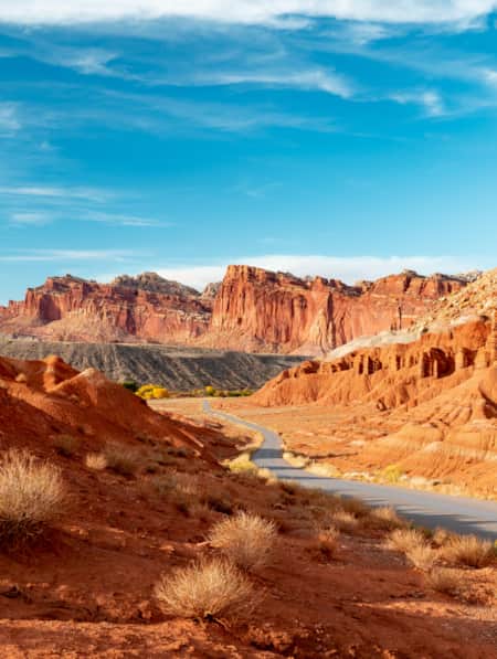 A road winding through a desert landscape, with large orange-hued rock formations on each side.