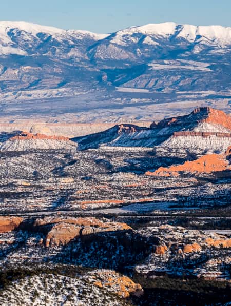 A landscape of rocky formations with sparse vegetation, all covered in snow.