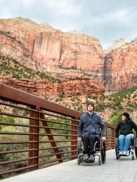 Two people in wheelchairs explore an accessible trail in Zion National Park.