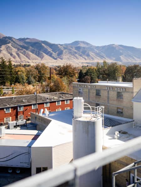 The view from the top of a building overlooking warehouses, with mountains visible in the distant backdrop.