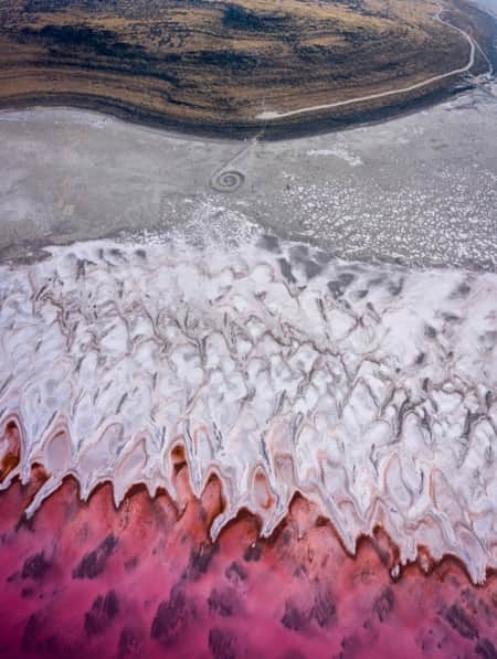 A spiral jetty extending into a lake with bright hues of yellow and red.